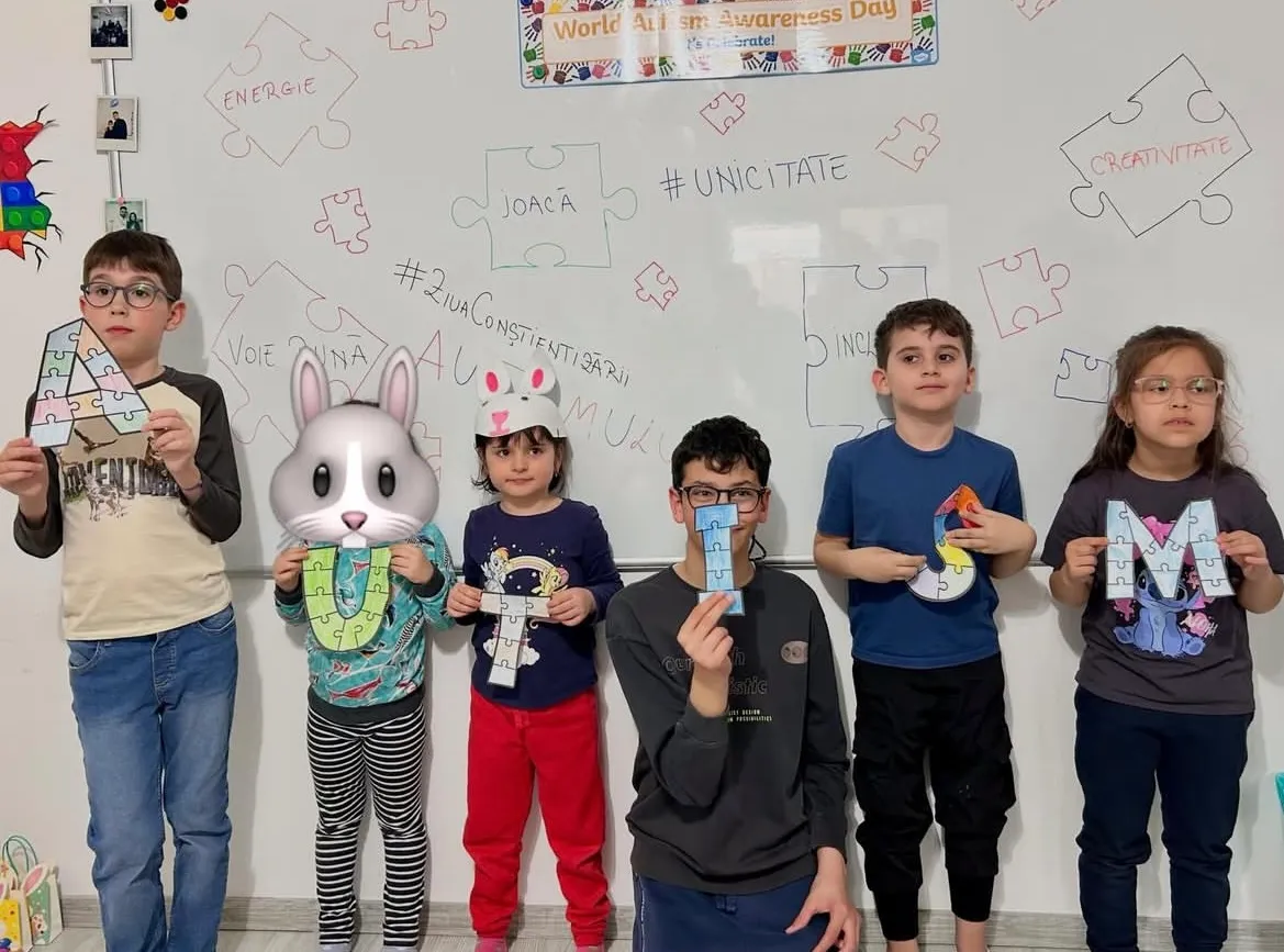 Copii țin litere-puzzle care formează cuvântul „autism” de Ziua Conștientizării Autismului
